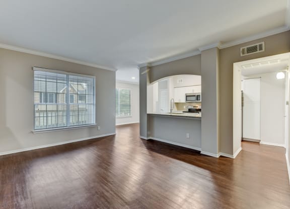 an empty living room with a large window and a kitchen