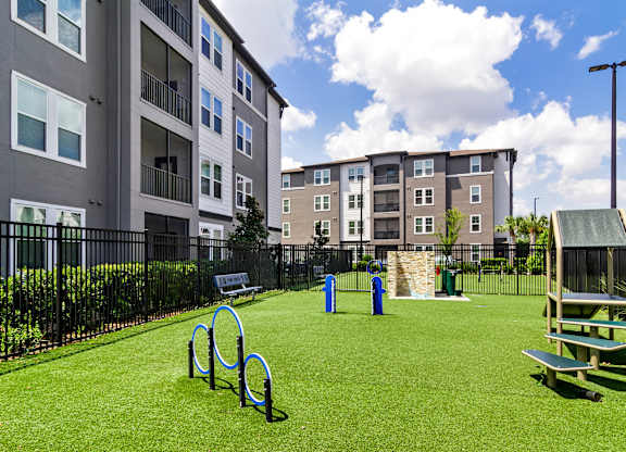 A playground with a green lawn, a slide, and a bench.
