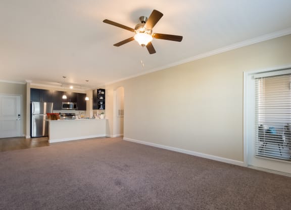 a living room with a ceiling fan and a kitchen in the background  at The Oasis at Manatee River, Bradenton, FL, 34211