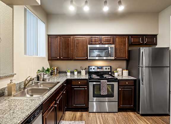 A modern kitchen with dark wood cabinets and stainless steel appliances.