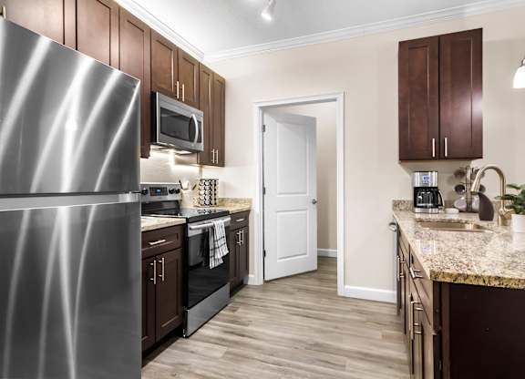 A kitchen with a stainless steel refrigerator and wooden cabinets.