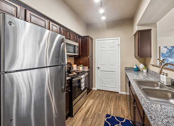 A kitchen with a stainless steel refrigerator and a sink.
