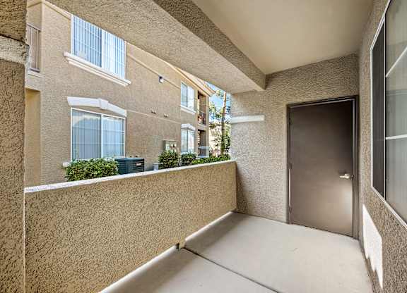 A balcony with a door and a wall with a window.