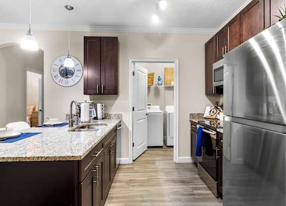 A kitchen with a refrigerator on the right and a sink with a faucet.