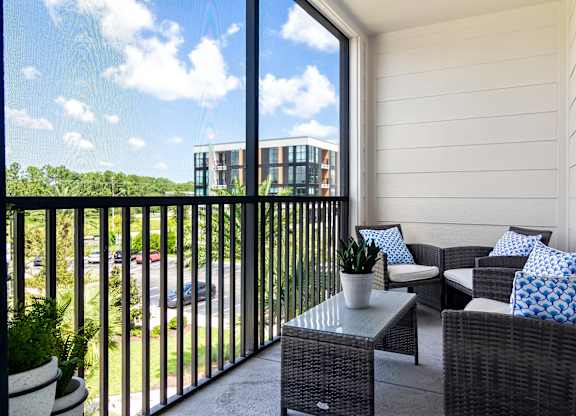 A balcony with a table and chairs overlooking a parking lot.