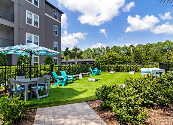 A patio with a table and chairs is surrounded by a black fence.
