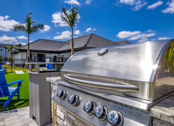 a stainless steel barbecue grill with a palm tree in the background at The Oasis at Manatee River, Bradenton, FL, 34211