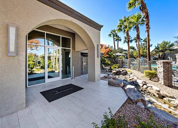 A modern house entrance with a stone wall and a black doormat.