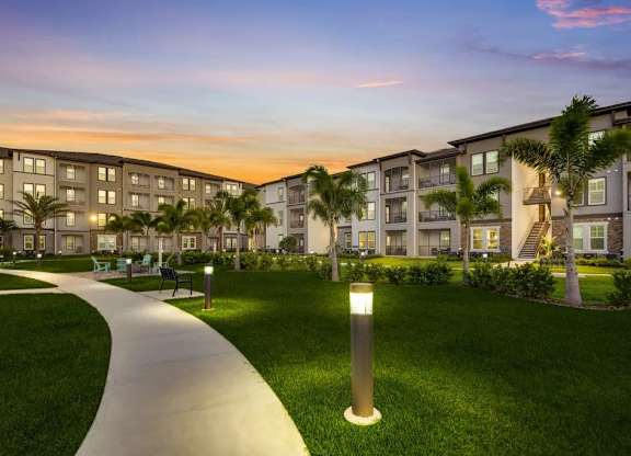 A modern apartment complex with a well-maintained lawn and walking path.