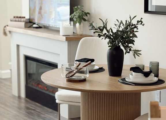 A modern dining room with a fireplace and a TV above it.