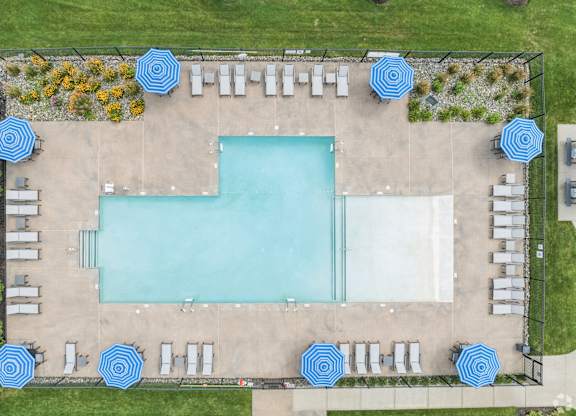 A large rectangular pool surrounded by blue umbrellas and lounge chairs.