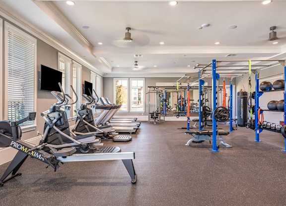 A gym with a variety of equipment including treadmills, weights, and exercise machines.