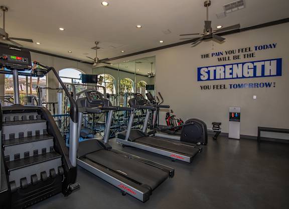 A gym with treadmills and a sign that says "The pain you feel today will be the strength you feel tomorrow!"