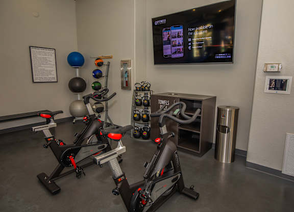 A gym with exercise bikes and a TV screen showing a news program.