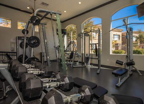 A gym with a variety of equipment including dumbbells, weight machines, and benches.