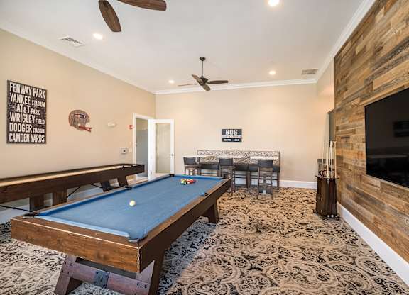 A pool table in a room with a wooden wall and a TV.