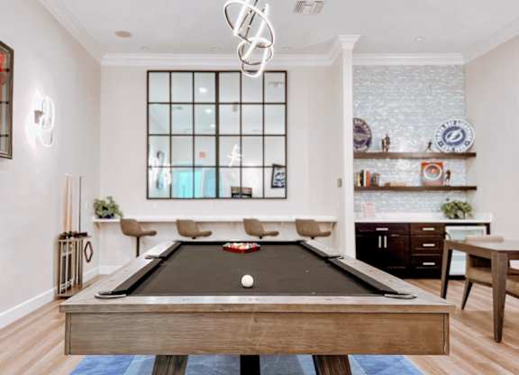 A pool table is in the middle of a room with a large window.