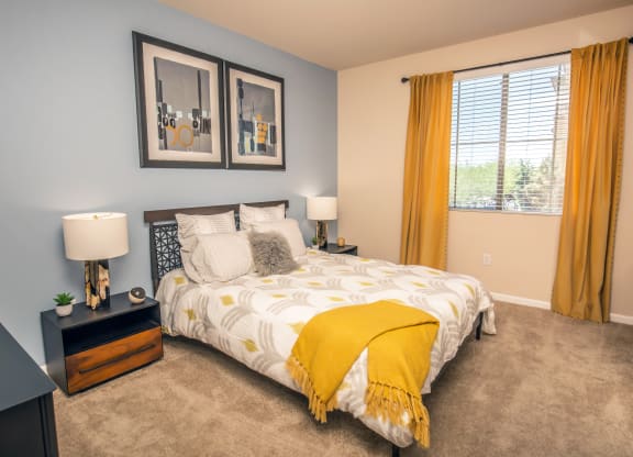 a bedroom with a yellow comforter and yellow curtains at Loreto & Palacio Apartments, Nevada 89149
