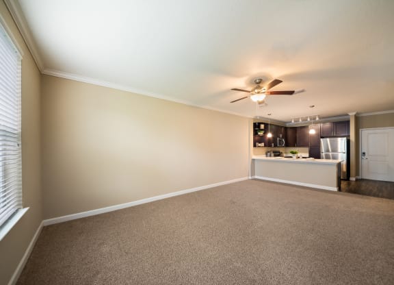 an empty living room and kitchen with a ceiling fan at The Oasis at Highwoods Preserve, Tampa, FL