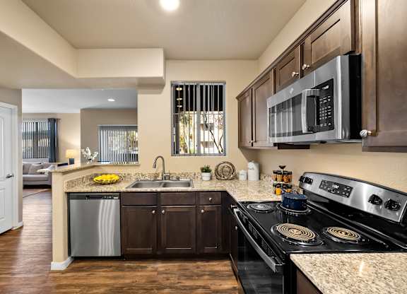 A modern kitchen with dark wood cabinets and stainless steel appliances.