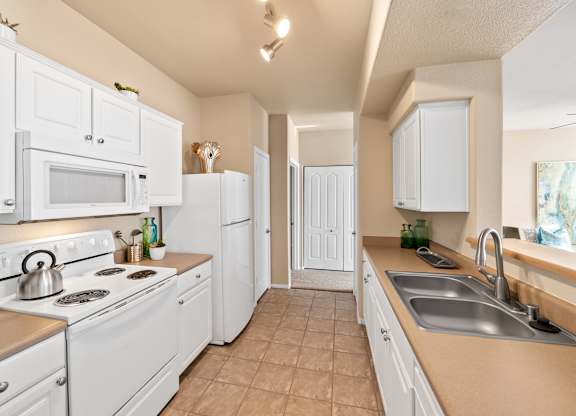 A kitchen with white appliances and cabinets.