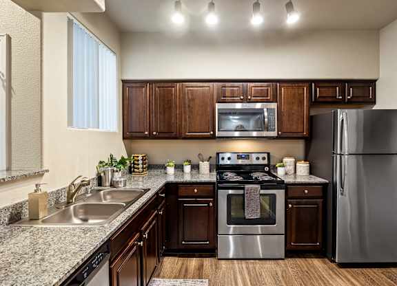 A modern kitchen with dark wood cabinets and stainless steel appliances.