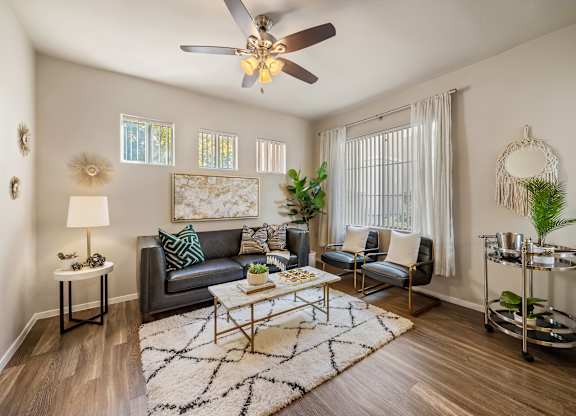 A living room with a grey couch, a coffee table, a ceiling fan, and a rug.