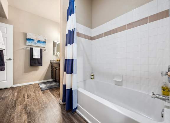 A bathroom with a white tub and a blue and white shower curtain.