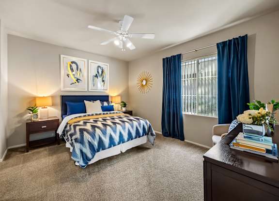 A bedroom with a bed, nightstands, and a ceiling fan.
