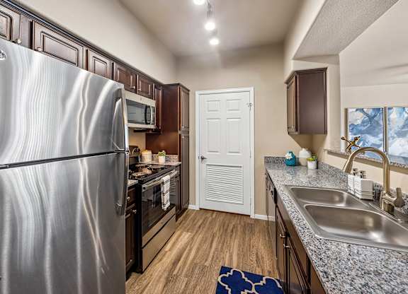 A kitchen with a stainless steel refrigerator and a white door.