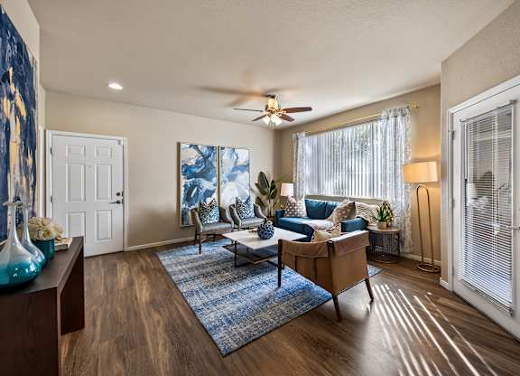 A living room with a blue rug and a wooden floor.