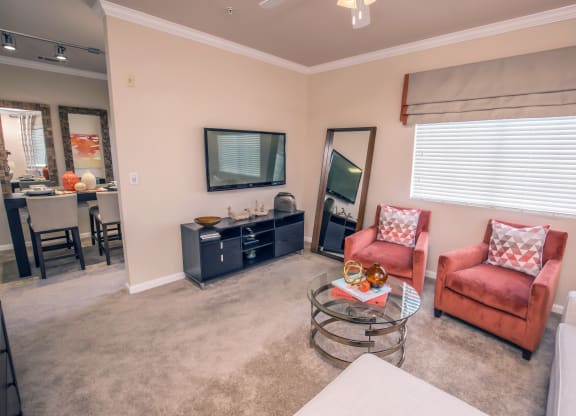 a living room with two red chairs and a glass coffee table at Loreto & Palacio Apartments, Las Vegas, NV 89149