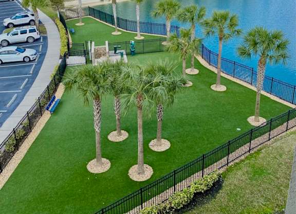 A row of palm trees are planted in a grassy area.