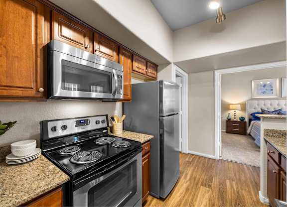 A kitchen with a black stove top oven and a black microwave above it.at The Equestrian by Picerne, Henderson, NV 89052