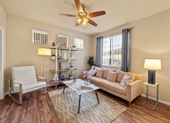 Living room with windows and casual comfortable furniture at The Fairways by Picerne Apartments, Las Vegas, NV