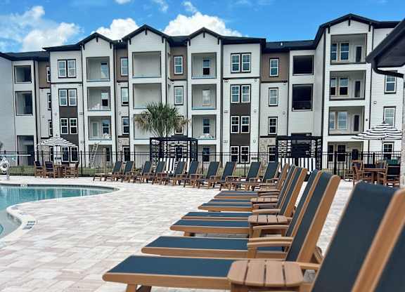A row of sun loungers are set up in front of a large apartment block.