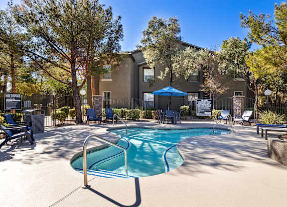 A pool surrounded by trees and chairs with a sign that says