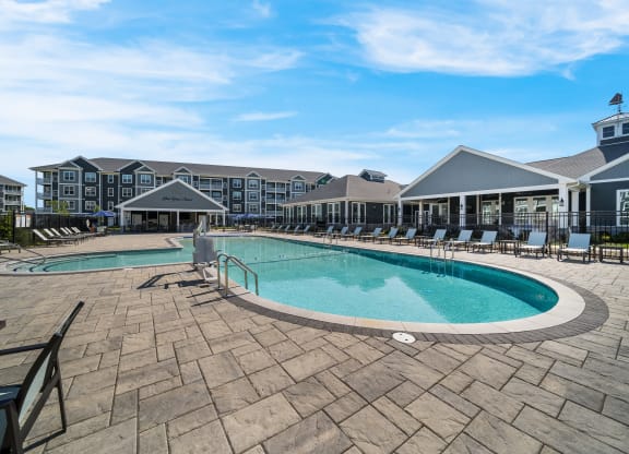 a resort style pool with chairs and a building in the background at The Oasis at Plymouth, Massachusetts