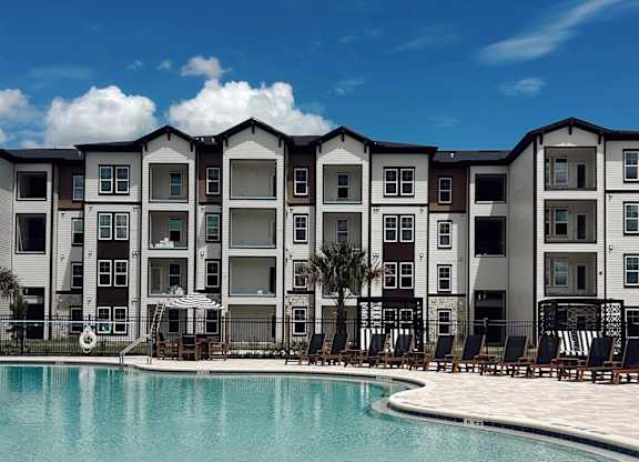 A large swimming pool in front of a building with a clear blue sky above.