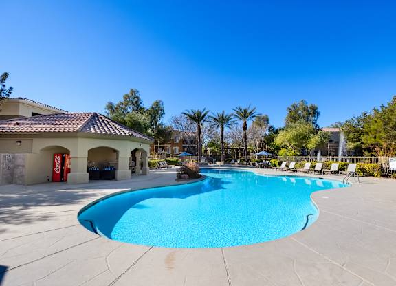 A large outdoor swimming pool with a sun lounger chairs around it.