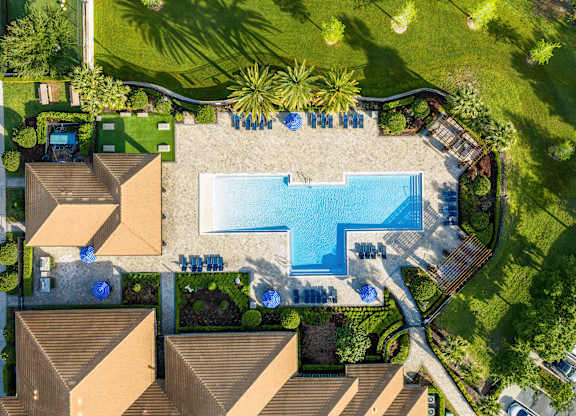 A swimming pool surrounded by a grassy area and a few trees.