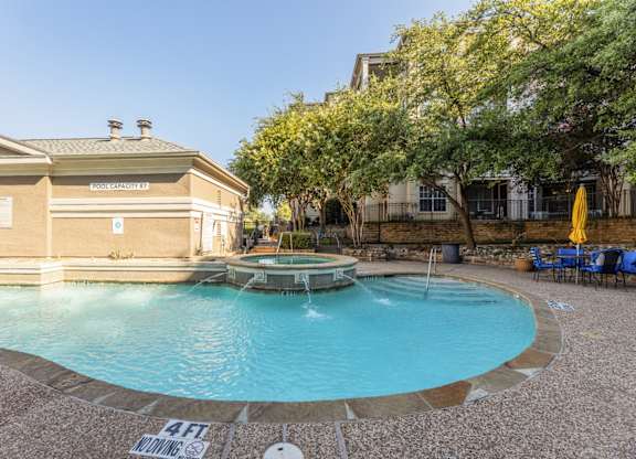 Swimming pool with a hot tub with small fountain feature and seating in the area at Encore at Buckingham apartments in Richardson, TX