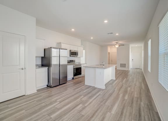 Open kitchen with white cabinets, a kitchen island, and stainless steel appliances of the Oak floor plan at Beacon at Clinton Corners in Dade City, FL