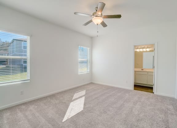 Bedroom with ceiling fan and two windows of the Oak floor plan at Beacon at Clinton Corners in Dade City, FL