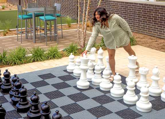 A woman playing a game of chess outdoors.