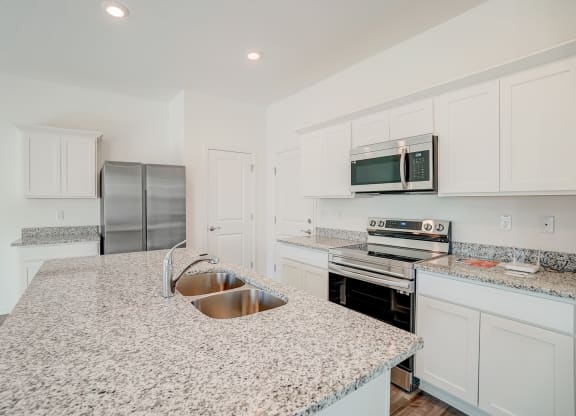 Kitchen with granite counter tops and stainless steel appliances in the Verbena floor plan at Beacon at Clinton Corners in Dade City, FL