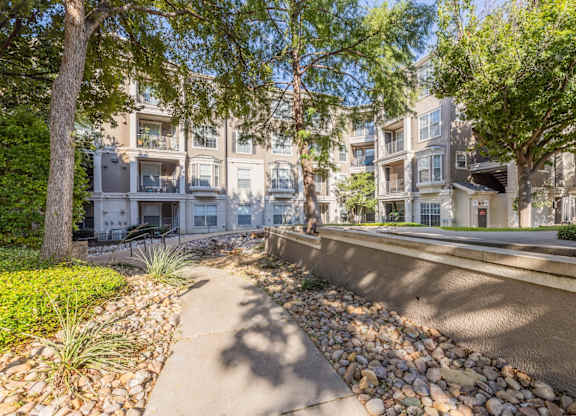 Walking paths within our community with lush trees at Encore at Buckingham apartments in Richardson, TX