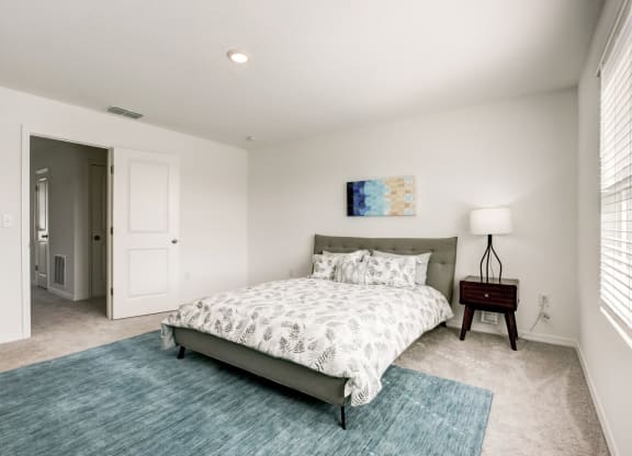Alternate view of master bedroom with blue rug and bed at Beacon at Arbours in Ruskin, FL