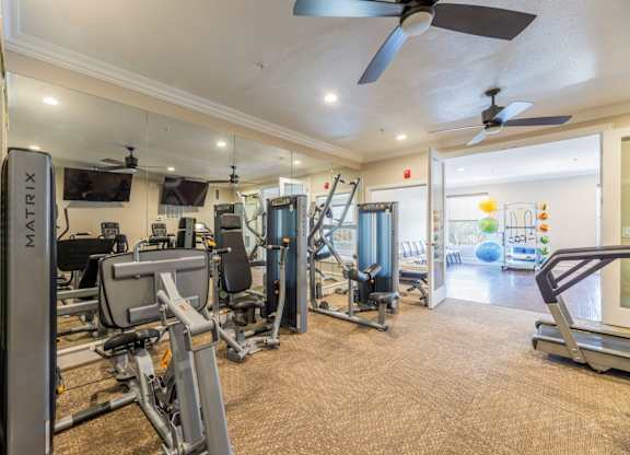 Cable machines including leg press, chest press, and lat pulldown machines in fitness center facing two tvs at Encore at Buckingham apartments in Richardson, TX