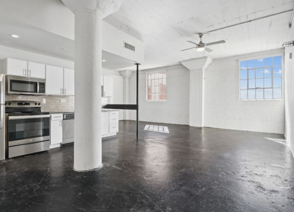 3200 Main large studio living space and kitchen with white cabinets and stainless steel appliances | Deep Ellum Lofts in Dallas, TX